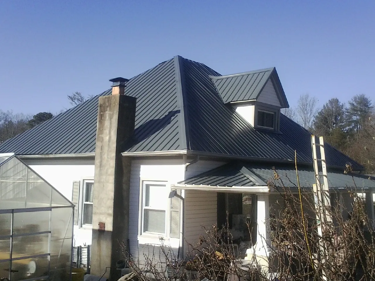 Dark blue standing seam metal roof on a white farmhouse with dormer — Slate & Tile Roof Repair by Roofing Brothers in Hayfield