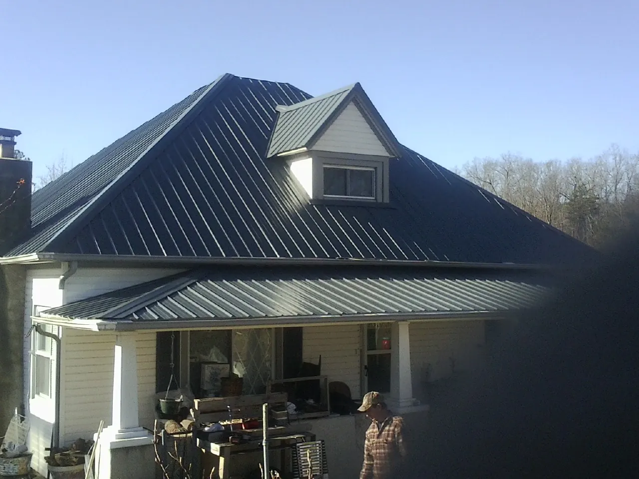 Dark blue standing seam metal roof with a dormer above a front porch in Hayfield