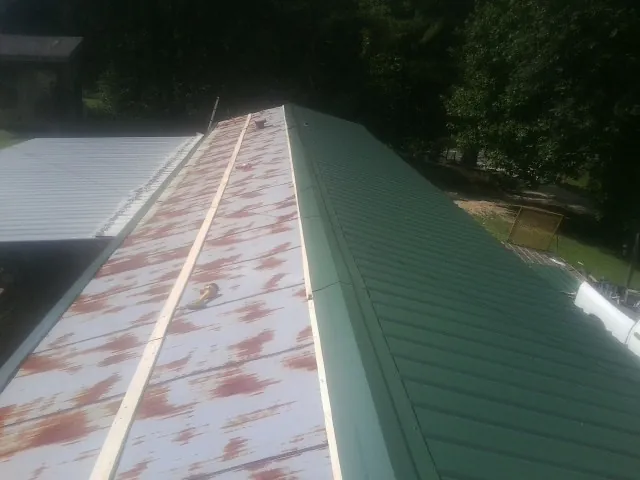 Old rusted panels beside newly installed green metal roofing — Wind Damage Roof Repair by Roofing Brothers in Hayfield