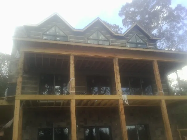 Dormers and porch framing on a large log home under construction — Roof Coating work by our crew in Hayfield