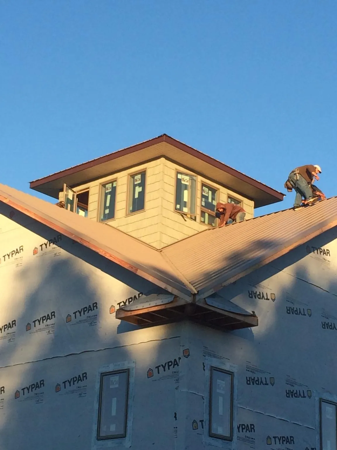 Roofers working around a rooftop cupola on a new metal roof at sunset — Roof Waterproofing in Hayfield by Roofing Brothers